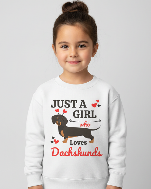 Smiling young girl modelling a white “Just A Girl Who Loves Dachshunds” kids sweatshirt in a bright studio setting.