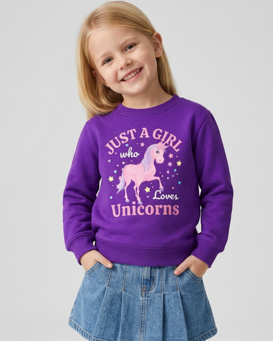 Young girl smiling with long blonde hair, wearing a purple "Just a Girl Who Loves Unicorns" crewneck sweatshirt and a blue denim skirt with her hands in her pockets.