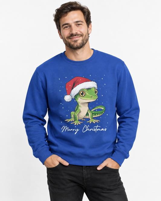 A man wearing a royal blue crewneck sweatshirt with a graphic of a green gecko wearing a red Santa hat and the text 'Merry Christmas' underneath, set against a plain white background.