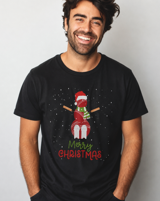 A smiling man wearing a black short-sleeve t-shirt with a festive cricket ball snowman Christmas graphic and the text 'Merry Christmas' printed on the front, set against a plain light grey background.