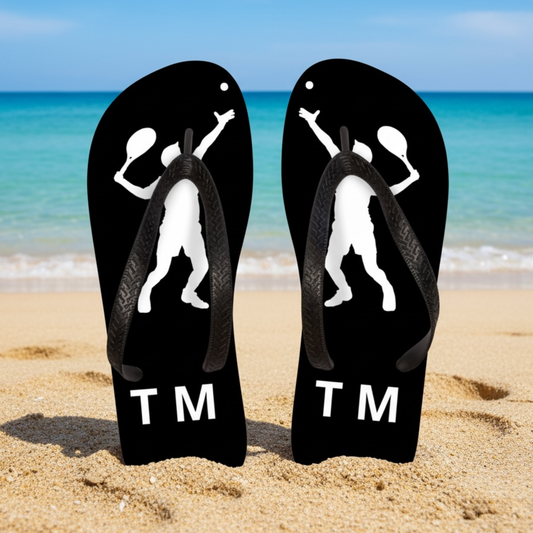 Personalised black tennis flip flops standing on a sandy beach with tennis player silhouette and custom initials.