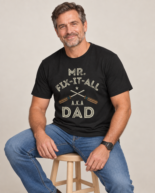 Man wearing a black Mr Fix-It-All AKA Dad T-shirt with crossed screwdriver graphic.