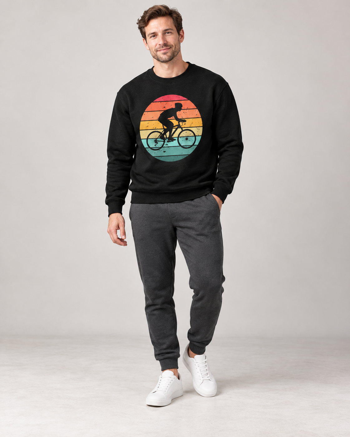 Man wearing a black retro sunset cyclist sweatshirt with dark-grey joggers and white trainers.