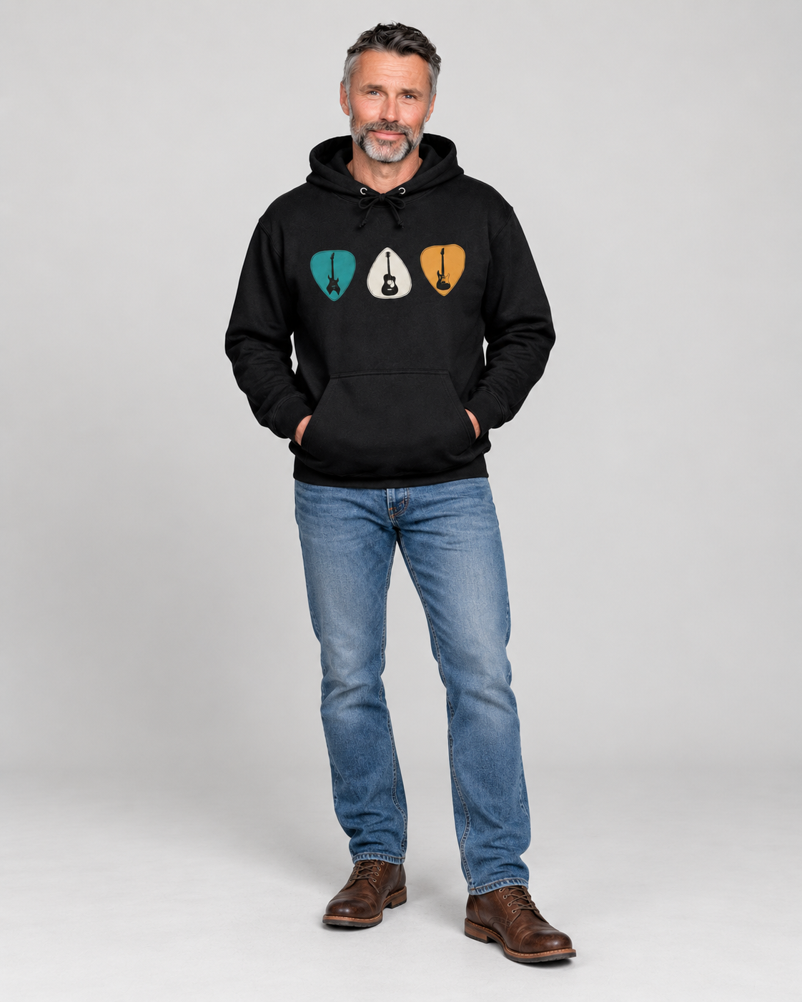 “Man wearing a black guitar hoodie with three colourful guitar plectrums, blue jeans and brown leather boots.”