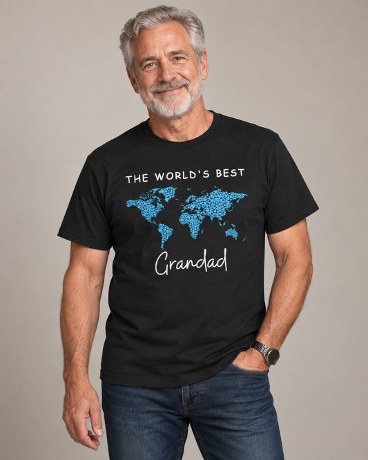 Smiling grey-haired man wearing a black “The World’s Best Grandad” T-shirt with a blue heart world map.