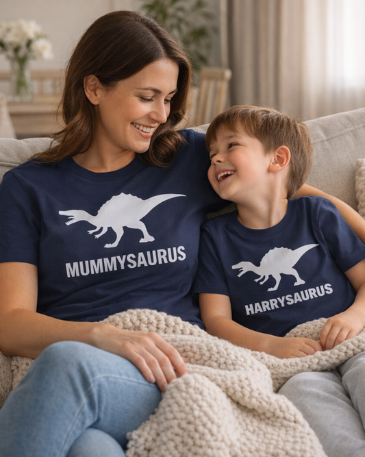 Woman and child sitting on a couch wearing matching 'Mummysaurus' and 'Harrysaurus' shirts.