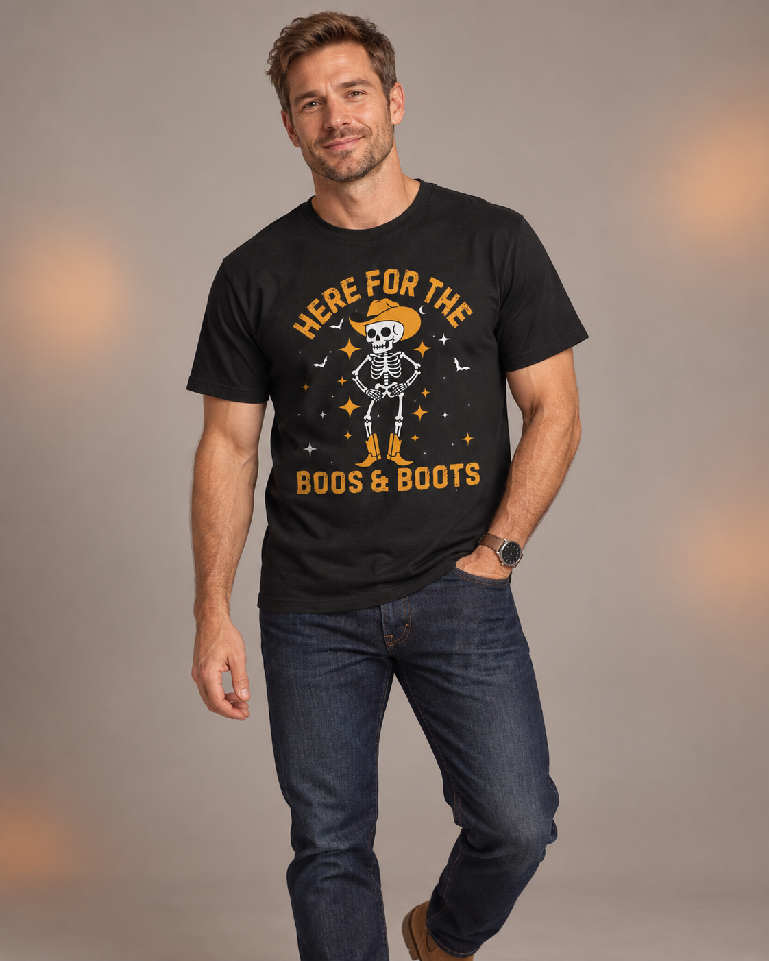 Man wearing a black “Here for the Boos & Boots” Halloween T-shirt featuring a cowboy skeleton, styled with dark jeans.