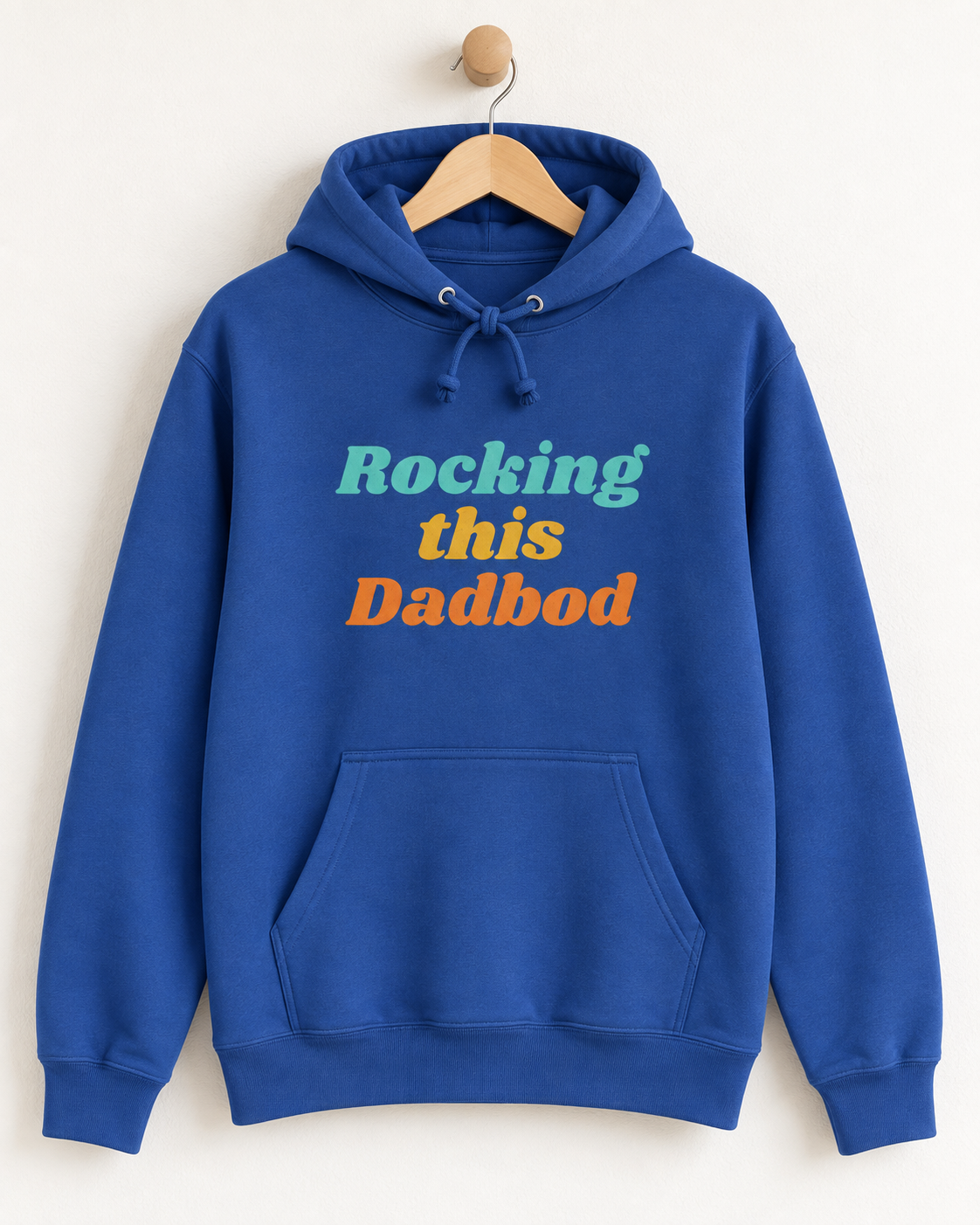 Royal blue “Rocking This Dadbod” men’s hoodie displayed on a natural wooden hanger and wall hook.
