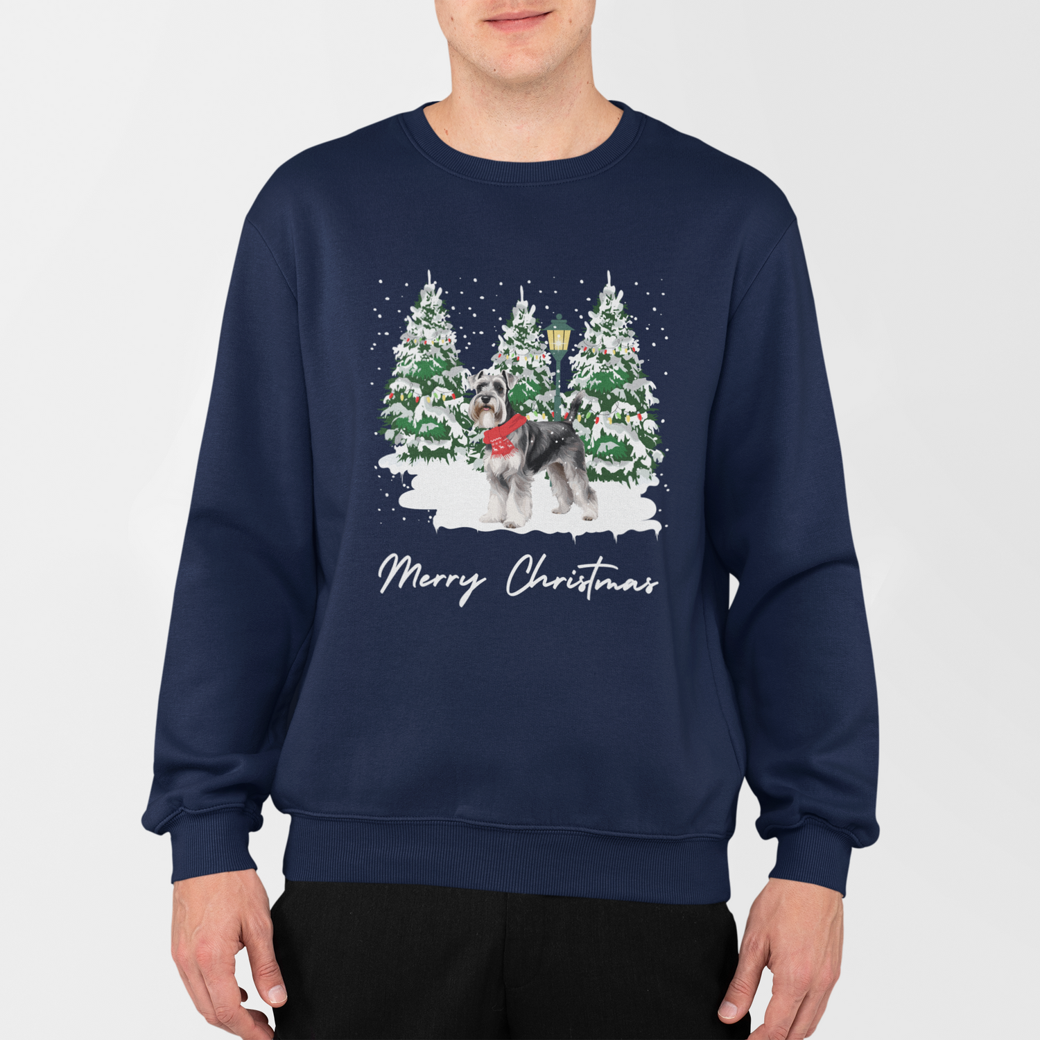 Man wearing a navy Christmas jumper featuring a schnauzer in a snowy Christmas tree scene with Merry Christmas text.