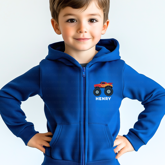 Young boy models a royal blue kids full-zip hoodie featuring a red and yellow monster truck printed on the left chest with the name “Henry” below the design.