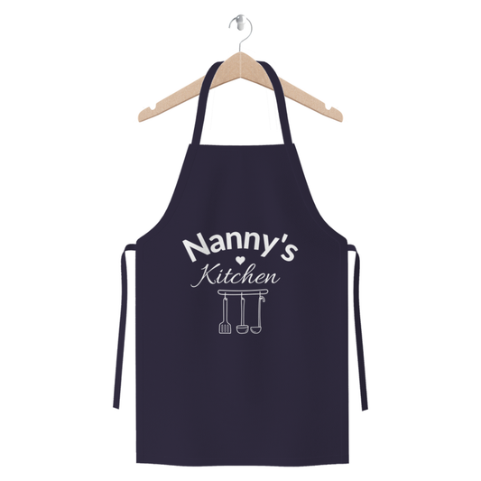 “Nanny’s Kitchen” navy apron with heart and hanging utensil illustration hanging on a wooden hanger.