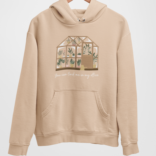 Beige hoodie with "You can find me in my office" and greenhouse graphic hangs on a wooden hanger.