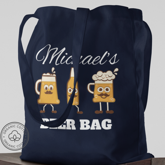 A navy organic cotton tote bag with a personalized name and a cartoonish beer mug design.