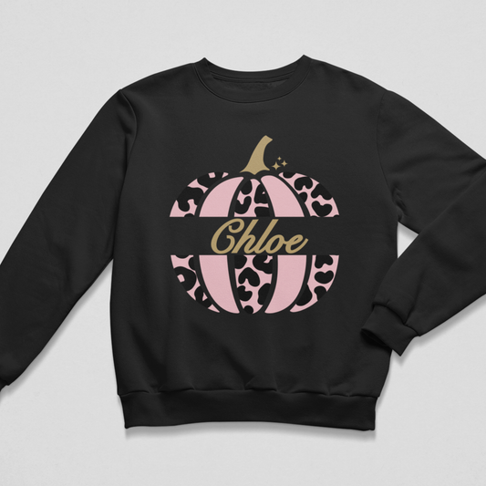 Personalised black kids’ Halloween sweatshirt with a pink leopard-print pumpkin and the name Hannah, displayed on a wooden hanger.
