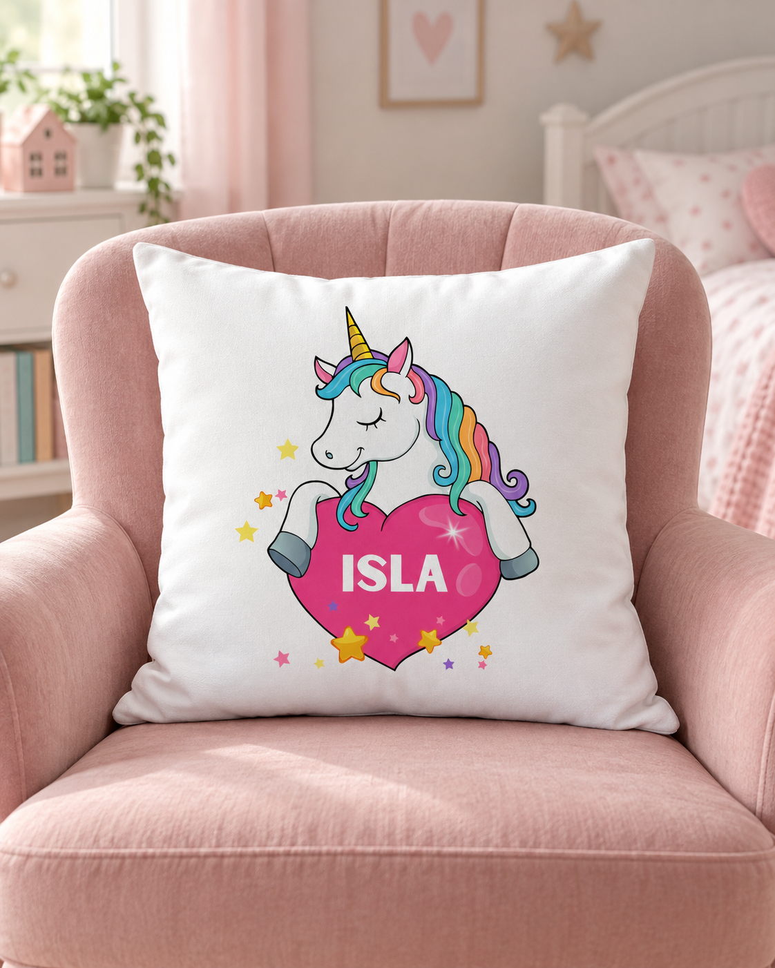 White personalised unicorn cushion with a rainbow mane, pink heart and name Isla, resting on a pink chair in a girl’s bedroom.