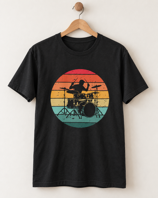 Black crew neck T-shirt on a wooden hanger against a light wall, displaying a colourful retro sunset and drum kit design.