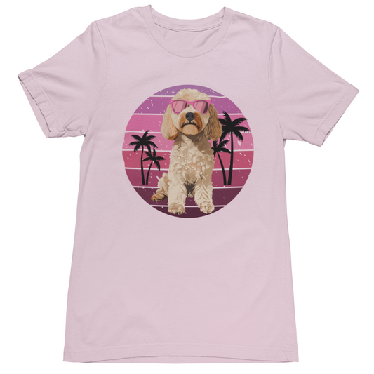 Soft pink t-shirt featuring a retro summer sunset circle with palm trees and a cockapoo wearing pink sunglasses graphic