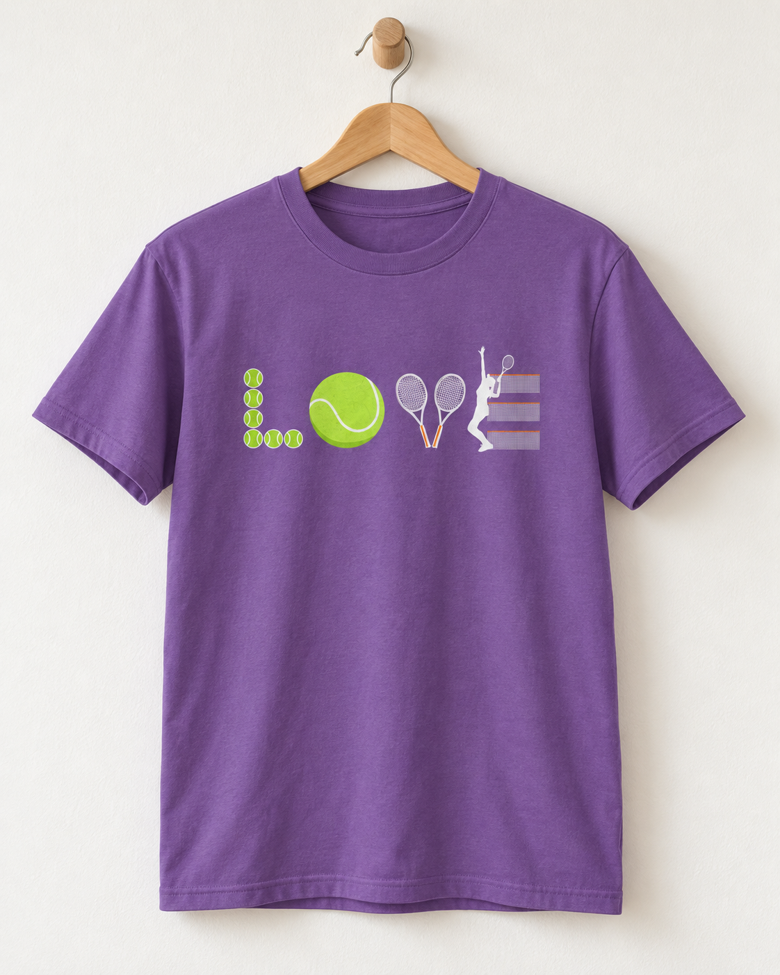 A purple short-sleeve crewneck t-shirt hanging on a wooden hanger against a light beige wall. The front of the shirt features a graphic design spelling 'LOVE' using tennis-themed icons: a stack of yellow tennis balls, a yellow tennis ball, two tennis rackets, and a white tennis player on a striped background.