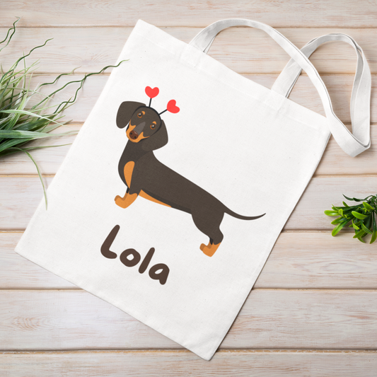 Children's white cotton tote bag with printed black and tan dachshund wearing red heart boppers with a personalised name