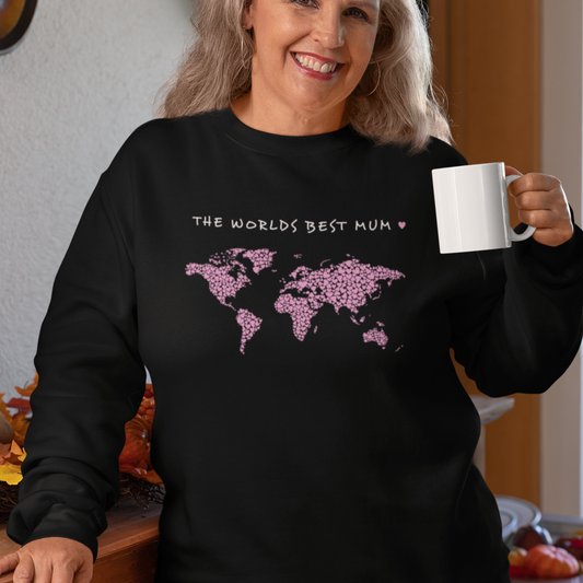 Woman smiling wearing a black sweatshirt jumper with a printed design of a world map made up of pink hearts, above states "The Worlds Best Mum"
