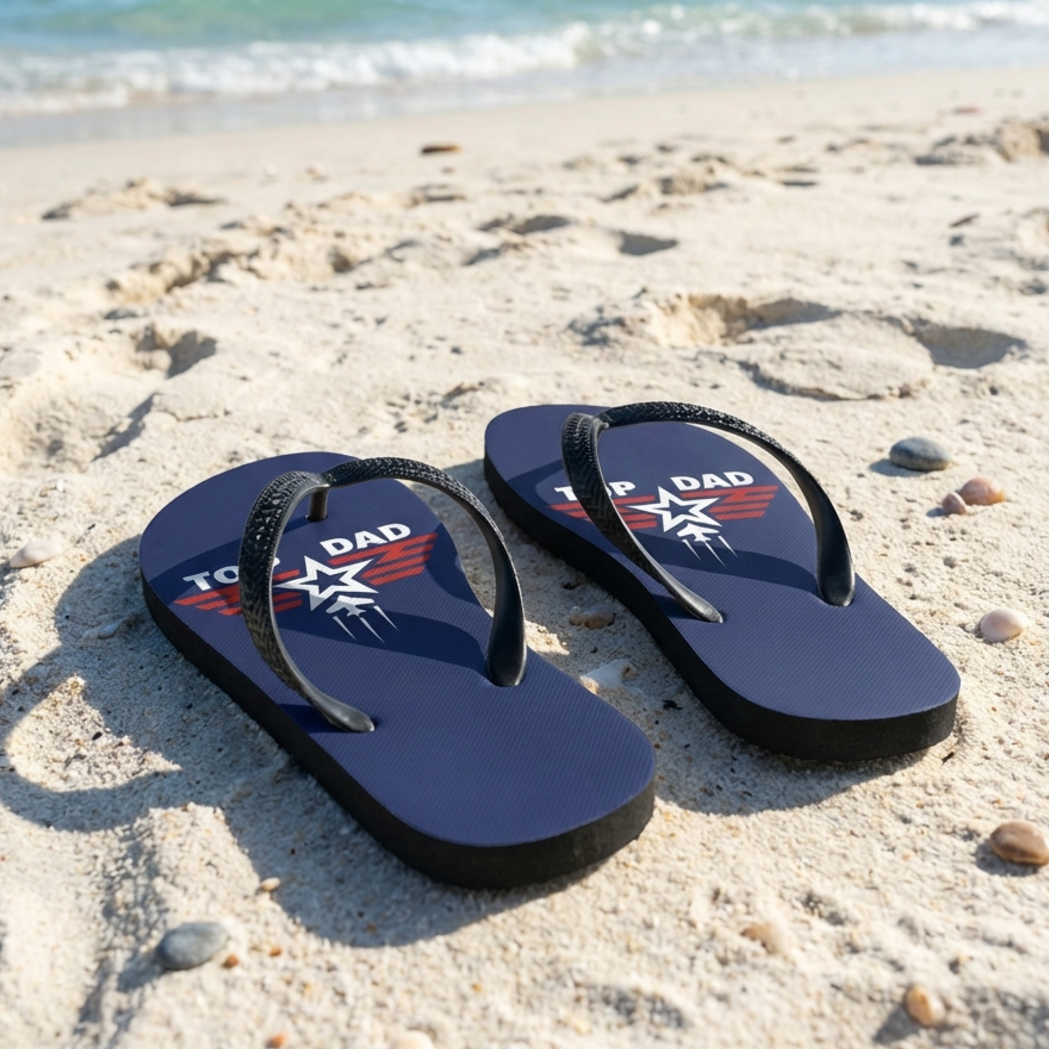 Top Dad navy flip flops with black straps on sandy beach near the sea, summer holiday footwear