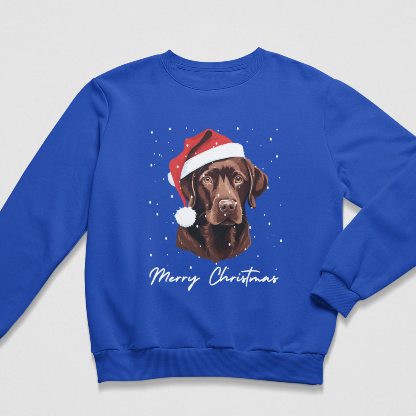 A royal blue crewneck sweatshirt featuring a graphic of a chocolate Labrador wearing a Santa hat, with 'Merry Christmas' written in white script below, displayed on a light gray background.
