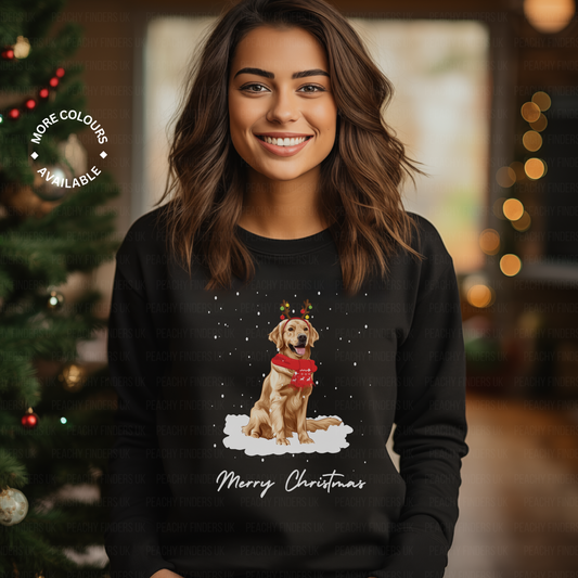Woman wearing a black Christmas-themed sweatshirt with a golden retriever dog illustration and 'Merry Christmas' text, standing in front of a decorated Christmas tree.
