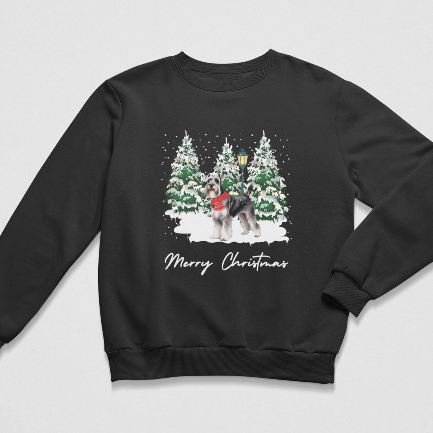 A black crewneck sweatshirt featuring a festive Christmas graphic of a schnauzer in a red sweater standing in front of snow-covered pine trees, with 'Merry Christmas' written below in white script.