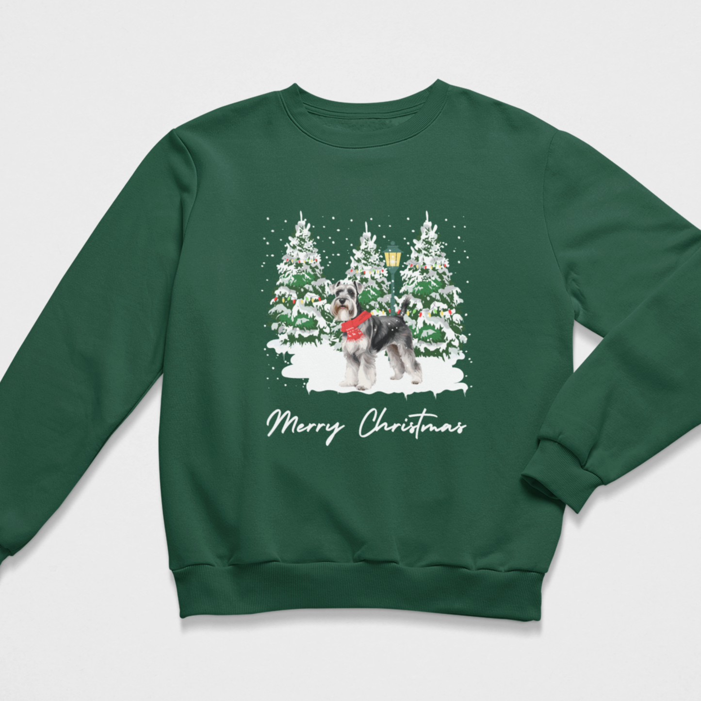 A dark green crewneck sweatshirt featuring a festive Christmas graphic of a schnauzer wearing a red scarf, standing in front of snow-covered pine trees with the text 'Merry Christmas' written below in white script.