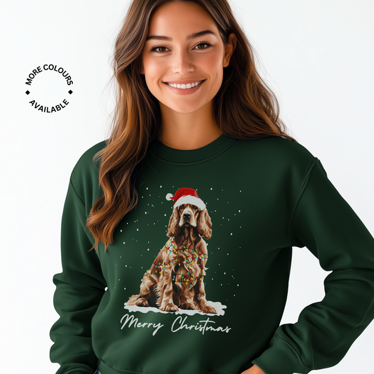 A woman smiling, wearing a green Christmas sweatshirt with a festive Cocker Spaniel design and the text 'Merry Christmas' on it.