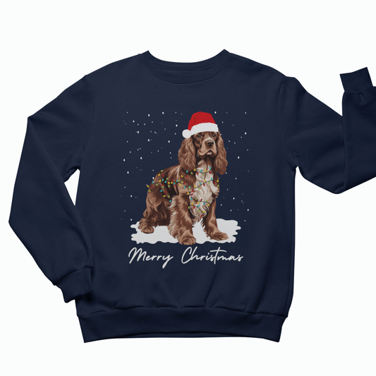 Navy kids Christmas sweatshirt with festive Cocker Spaniel wearing a Santa hat, surrounded by snow and Christmas lights.