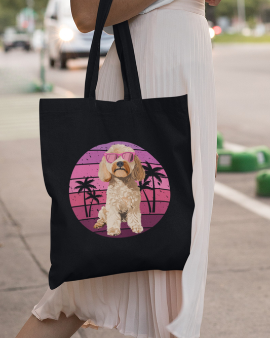 Woman carrying black tote bag with cockapoo in pink sunglasses, retro sunset background and palm trees