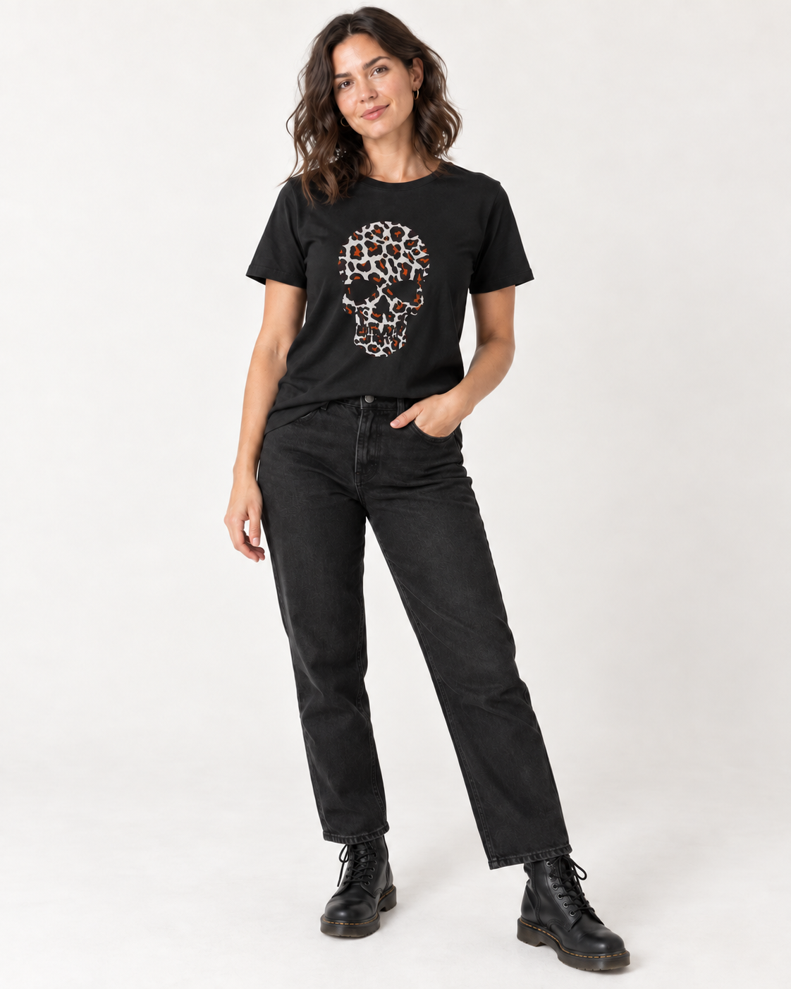 Woman wearing a black T-shirt with a white, black and orange leopard-print skull design, styled with black jeans and ankle boots.
