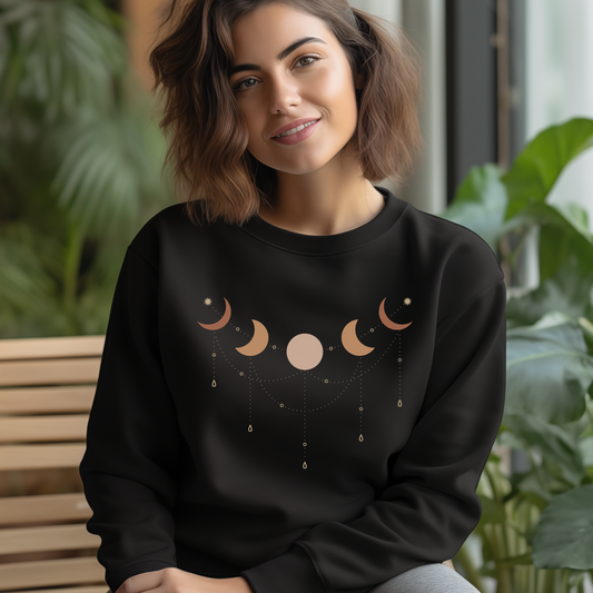 Woman wearing black organic cotton sweatshirt with luna phases of the moon celestial design, indoor lifestyle photo