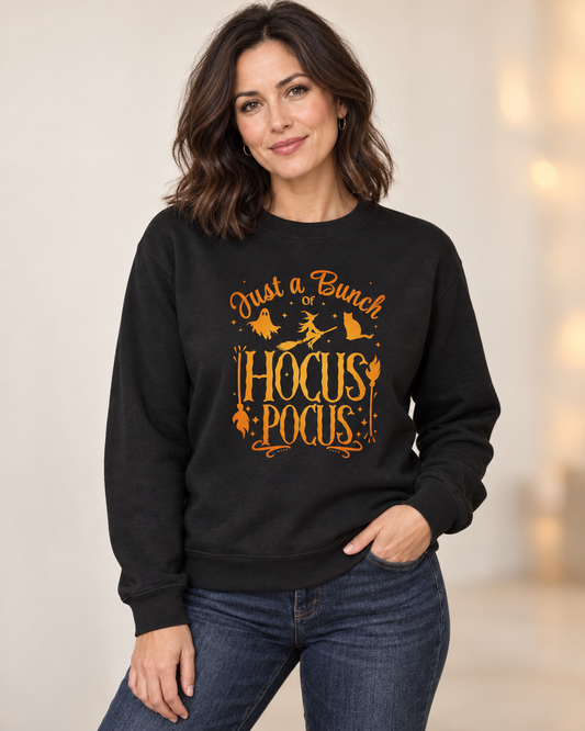 Woman wearing a black Halloween sweatshirt featuring orange “Just a Bunch of Hocus Pocus” lettering with a ghost, flying witch and cat design.