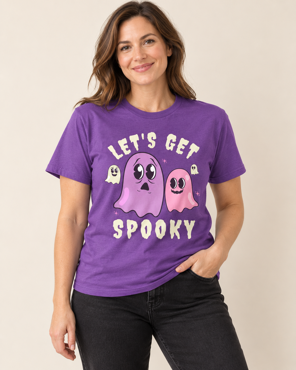 Woman wearing a royal purple “Let’s Get Spooky” T-shirt with pink and purple ghosts, paired with black jeans.