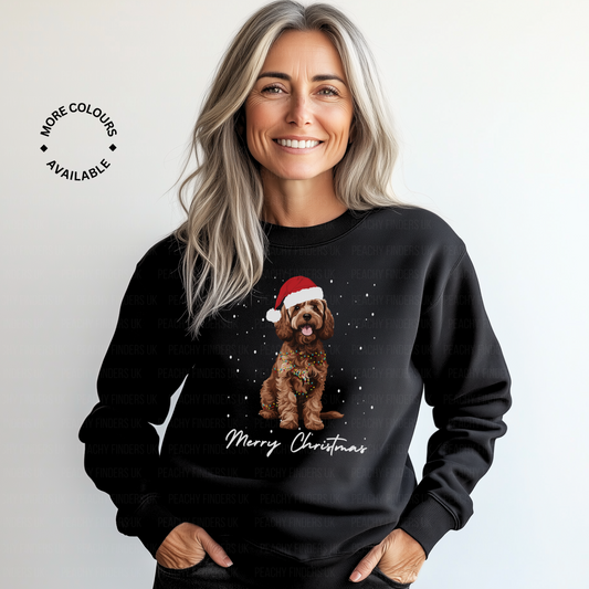 Woman wearing a black Christmas-themed sweatshirt with a brown cockapoo wearing a Santa hat and 'Merry Christmas' text.