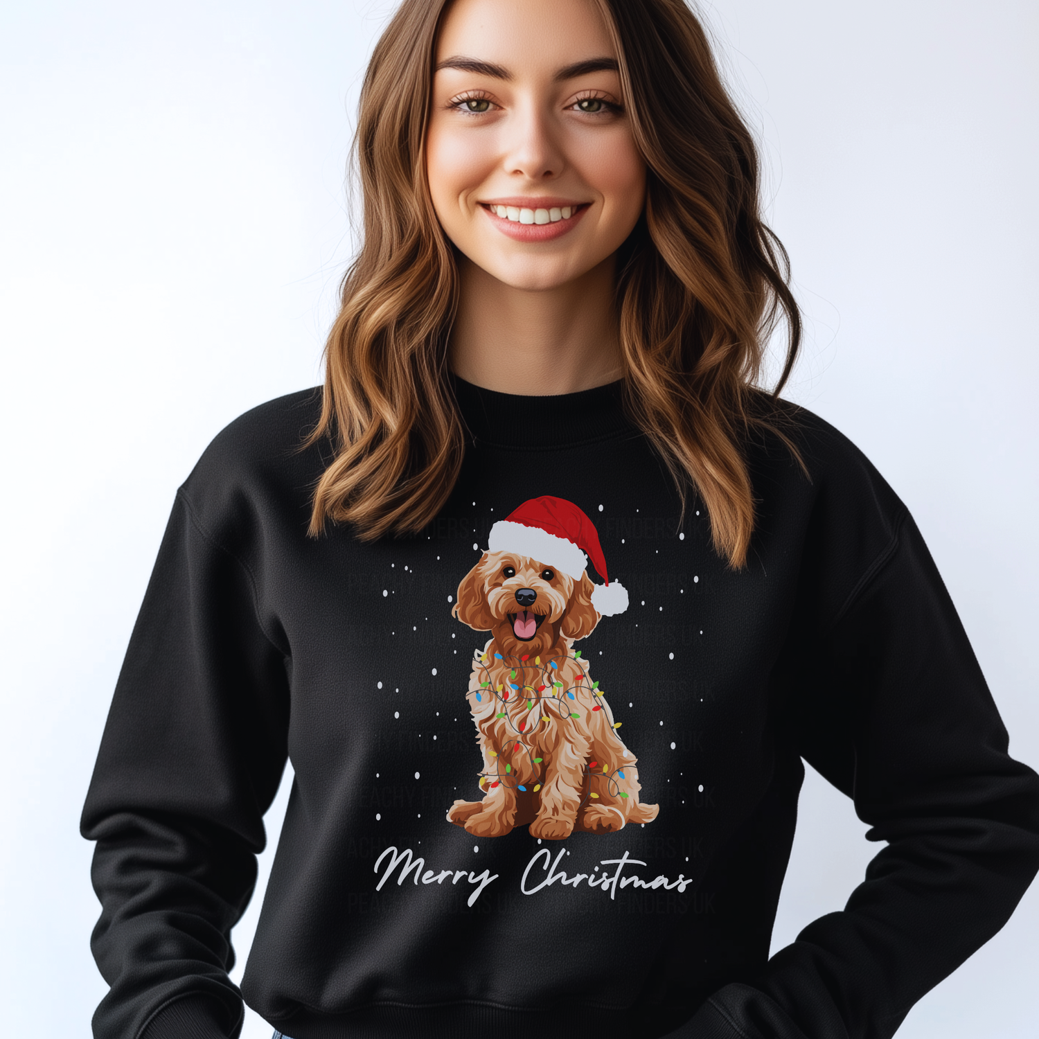 Woman wearing a black Christmas-themed sweatshirt with a golden cockapoo wearing a Santa hat, wrapped in fairy lights and 'Merry Christmas' text.