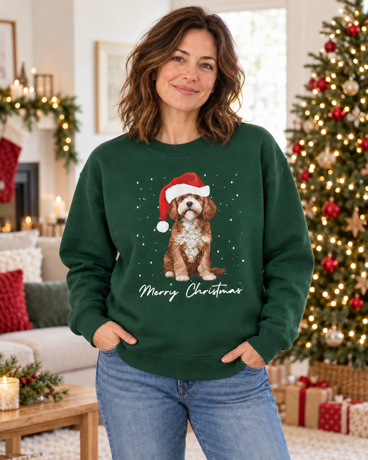 Woman wearing the dark green Christmas Cavapoo jumper paired with jeans, standing in a cosy living room beside a decorated Christmas tree.