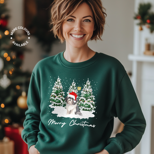 A woman wearing a dark green Christmas-themed sweatshirt with a cute Shih Tzu dog wearing a Santa hat in the snow and winter scene design.