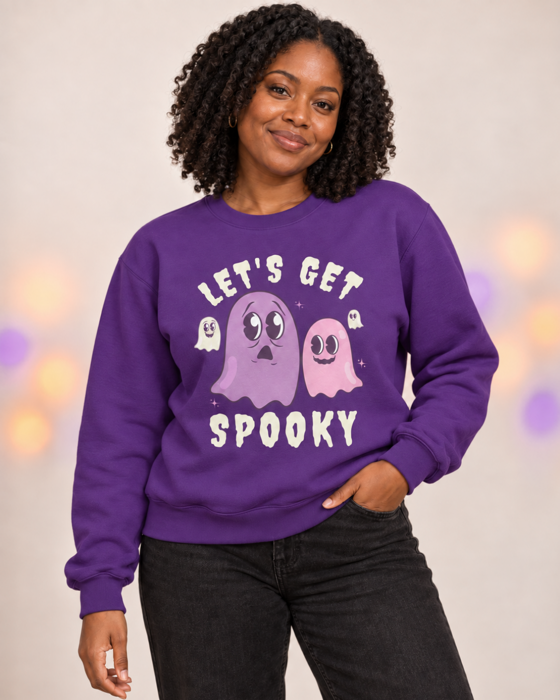 Black woman wearing a purple “Let’s Get Spooky” Halloween sweatshirt featuring pink and lilac retro ghost characters.