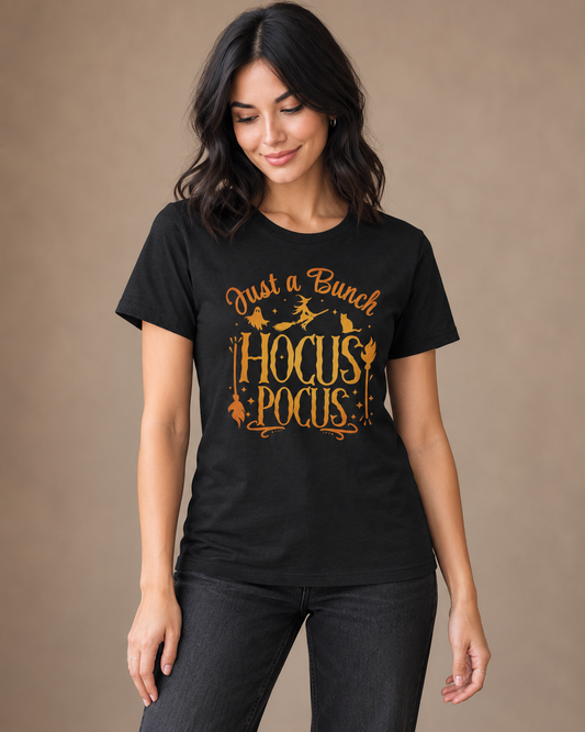 Woman wearing a black Hocus Pocus Halloween T-shirt with orange witch, ghost and cat artwork and black jeans.