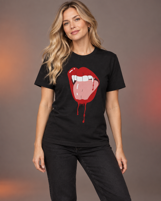 Blonde woman wearing a black Halloween T-shirt featuring red vampire lips, white fangs and dripping blood, styled with black jeans.