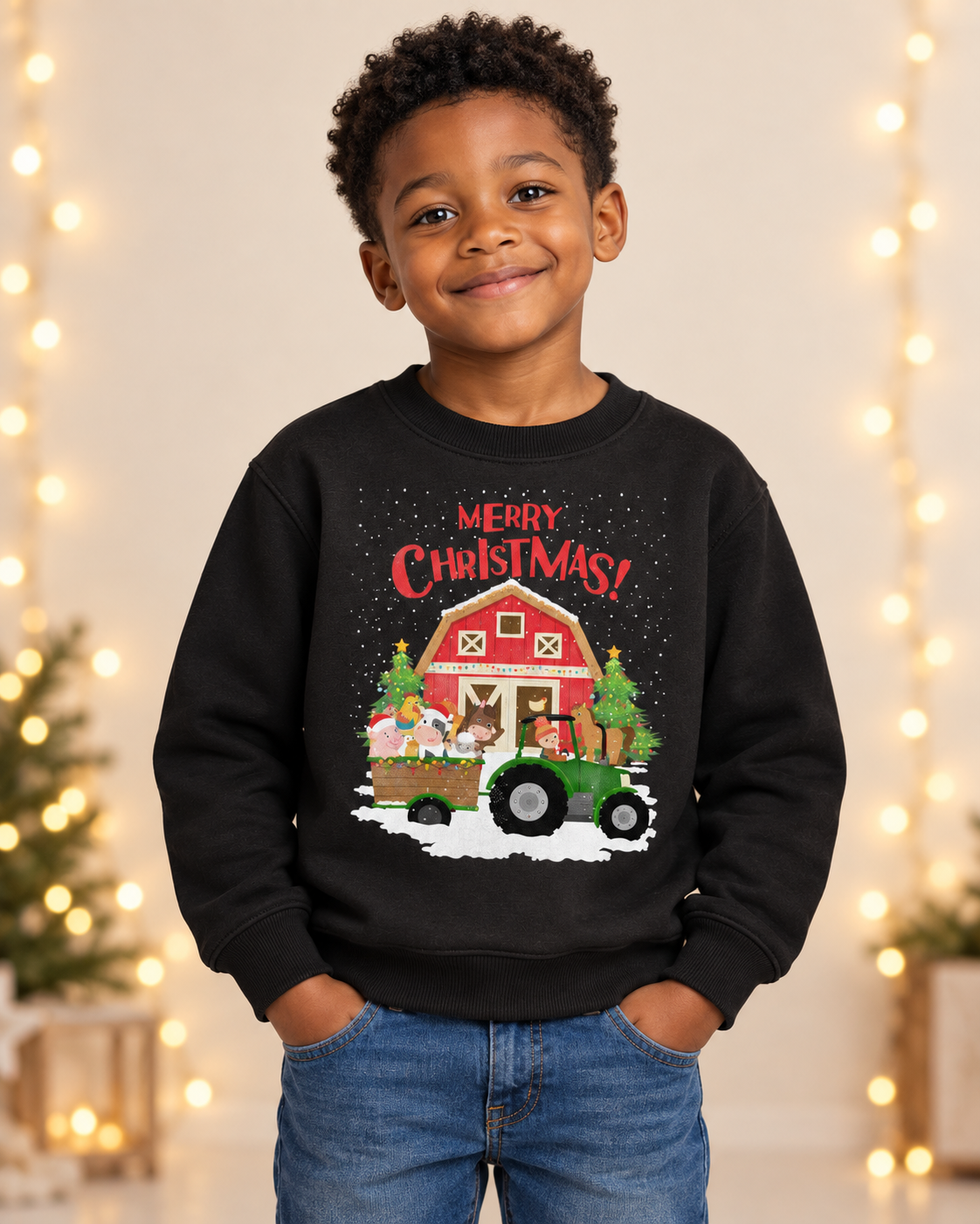 Young boy smiling while wearing a black Christmas sweatshirt featuring a green tractor and festive farm animals in front of a snowy red barn.