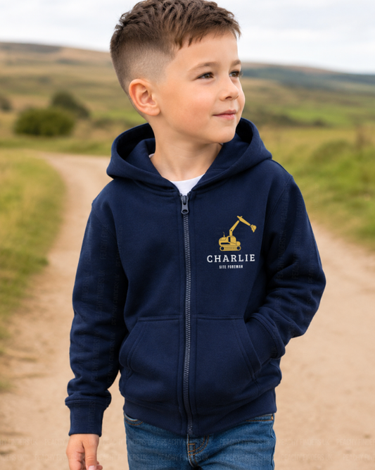 Young boy wearing a personalised navy digger site foreman zip hoodie with custom name Charlie, standing outdoors on a countryside track.