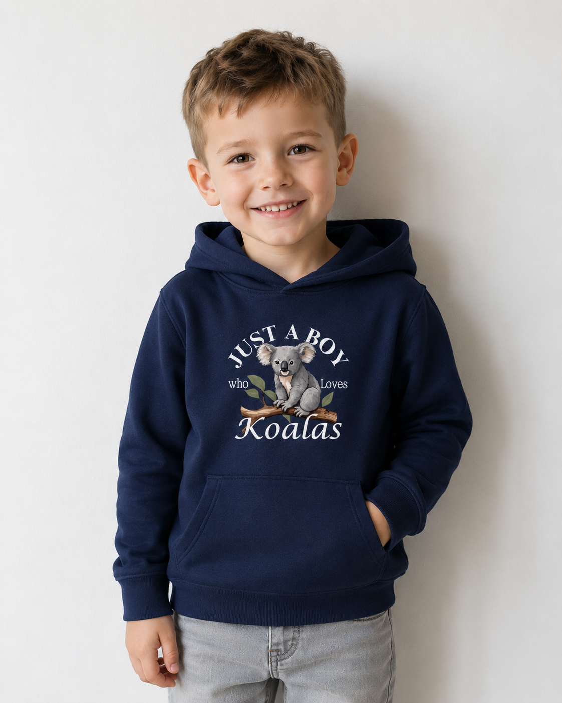 Young boy modelling a navy kids koala hoodie with “Just a Boy Who Loves Koalas” design and light grey jeans in a studio photo