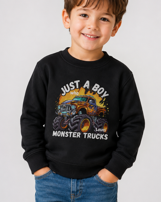 Young boy wearing a "Just A Boy Who Loves Monster Trucks" black sweatshirt with jeans in a studio photoshoot.
