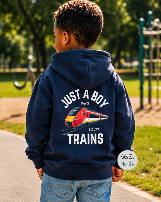 Young boy wearing a navy kids zip hoodie with a large back print featuring a modern red train and the slogan "Just A Boy Who Loves Trains", standing in a sunny park.