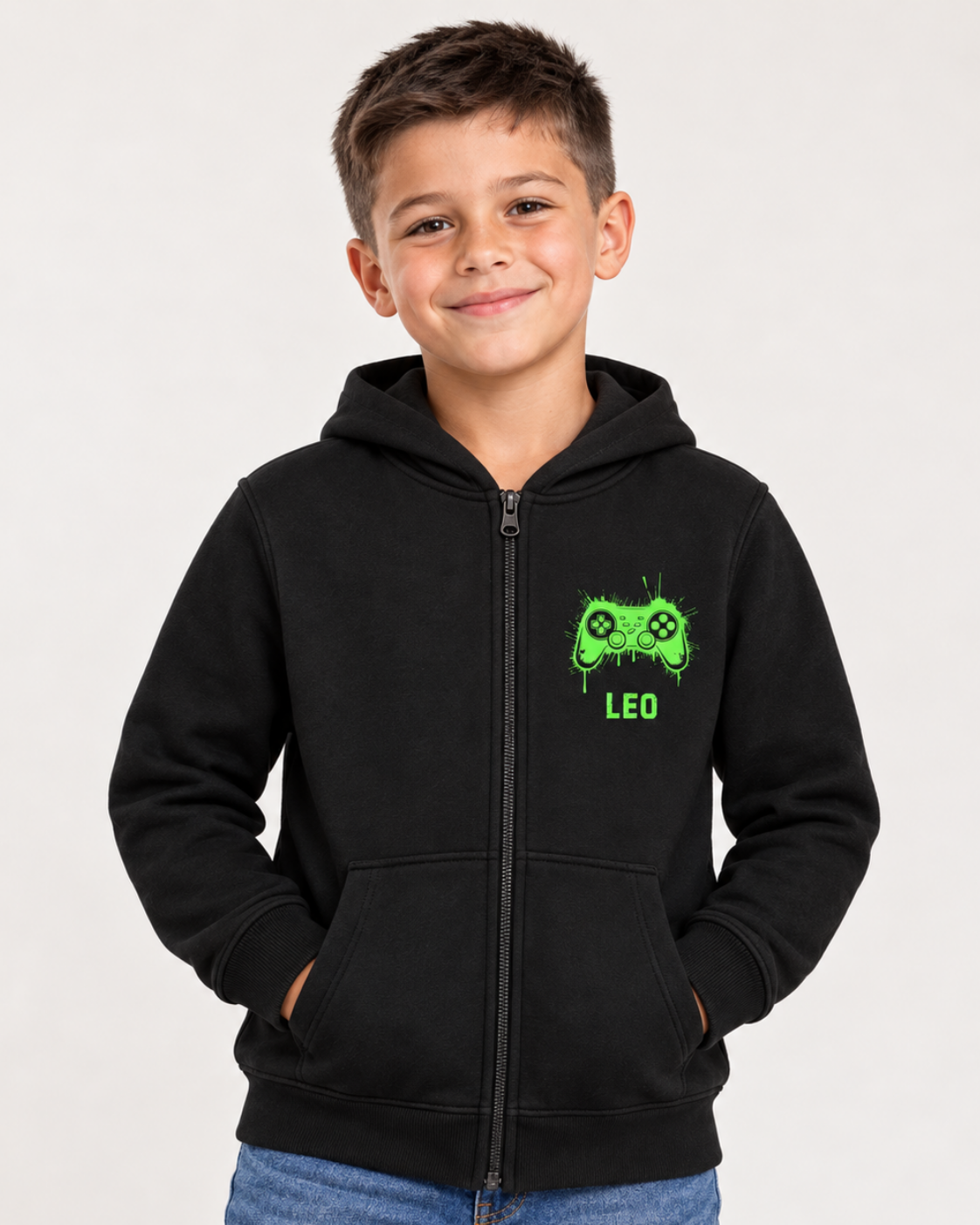 Smiling boy wearing a black personalised gamer zip hoodie with Leo printed below the bright green controller, hands tucked into the pockets.