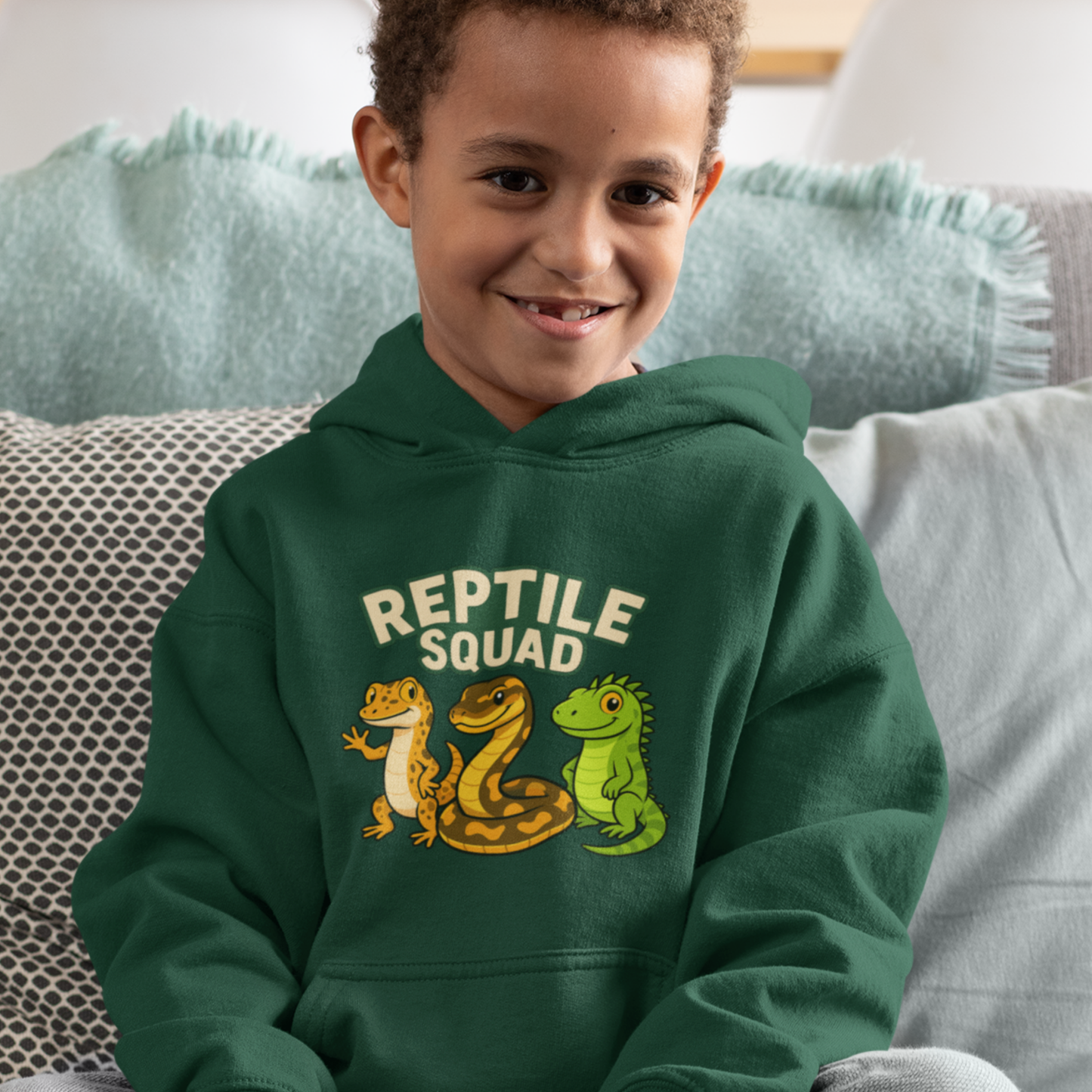 Child wearing a green hoodie with 'Reptile Squad' design sitting on a couch.